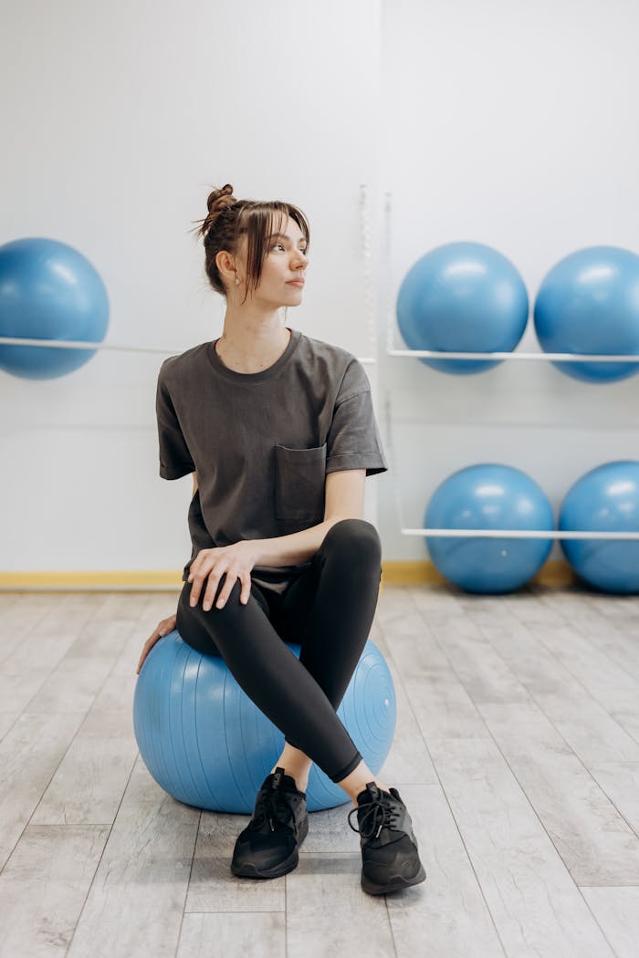 A woman sitting on a yoga ball indoors, promoting a healthy and mindful lifestyle.